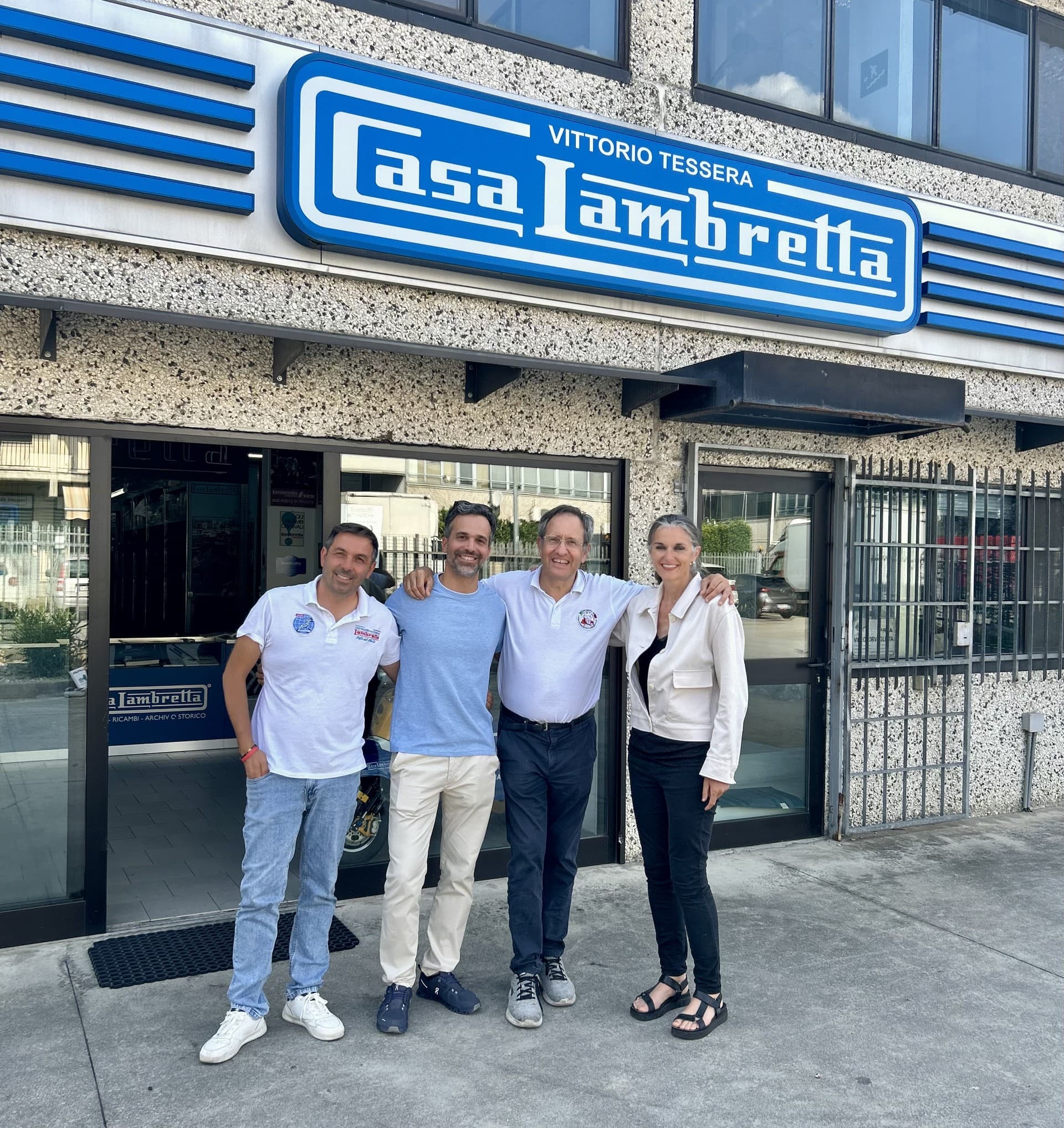 Three men and a lady smiling proudly outside the Casa Lambretta in Milan